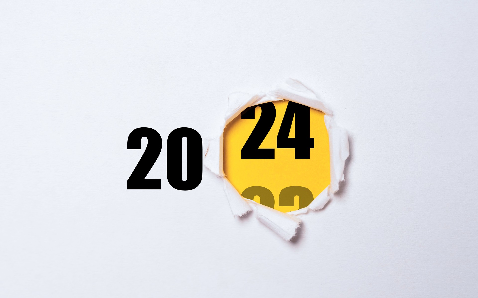 Changing of year from 2023 to 2024 inside of yellow punch paper for start business preparation in new year concept.